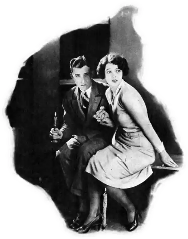 A young man and woman in fancy dress look with fear holding a candle
