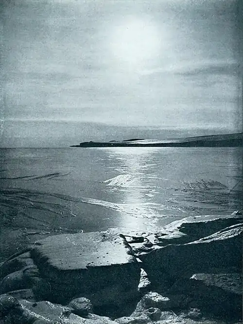 Photo from shore of a smoothly-iced bay