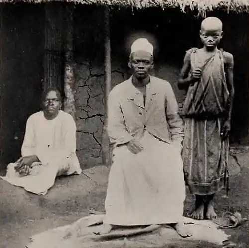 Two men seated with a boy standing next to them