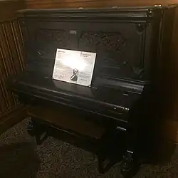 An old, black piano with a piece of paper on it.