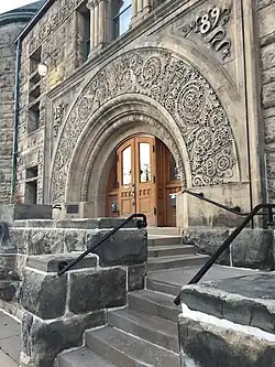 Big wooden doors under a large stone arch. The front entrance of the Mabel Tainter Center of the Arts.